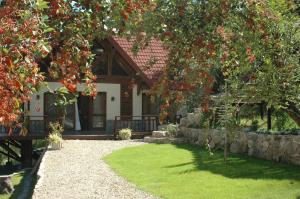 a house with a stone wall and a tree with red flowers at Arroyo Escondido in La Cumbrecita