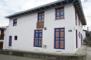 un edificio blanco con puertas y ventanas coloridas en Hostal Familiar Jerico, en Salento