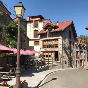 uma luz de rua em frente a um edifício com mesas e guarda-sóis em Hotel Rural Peña Castil em Sotres