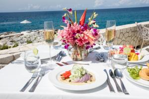 una mesa con platos de comida y un jarrón de flores en The Cliff Hotel en Negril