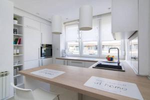 札格雷布的住宿－Apartment Sarita，厨房配有白色橱柜和带桌子的柜台。