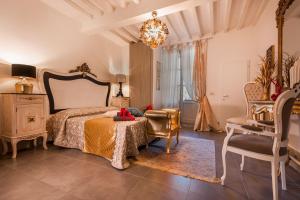 a bedroom with a bed and a chair and a chandelier at Sweet Tuscany Appartamento Gold in Arezzo
