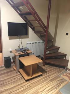 a living room with a desk and a tv and stairs at Villa Aleksandar in Kopaonik
