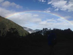 a person standing in a field with a rainbow in the sky at Casa Divina Eco Lodge in Mindo