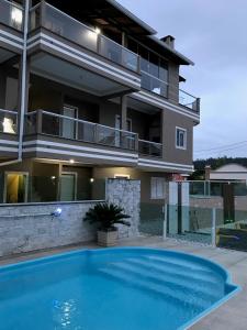 a house with a swimming pool in front of a building at Residencial Flat Debora in Florianópolis