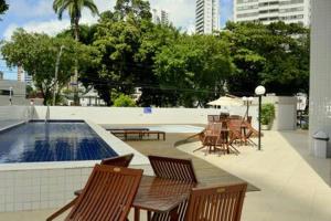 un patio con mesas y sillas junto a una piscina en Flats Rosarinho Prince Prime, en Recife