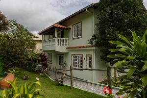a green house with a balcony and a yard at Itaporanga Pousada in Santa Maria Madalena