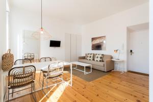 uma sala de estar com uma mesa e cadeiras e um sofá em Chiado Cozy Apartments - by LU Holidays em Lisboa