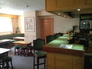 a restaurant with green counters and tables and chairs at Hall Park Hotel in Workington