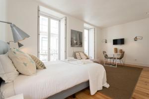 a white bedroom with a large bed and a table at Chiado Cozy Apartments - by LU Holidays in Lisbon