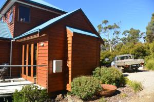 a small wooden house with a truck parked next to it at The Tree House in Alonnah