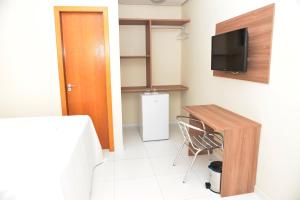 Habitación pequeña con escritorio y TV. en Cajueiro Hotel, en Floriano