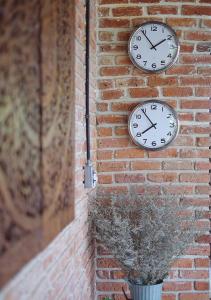 two clocks on the side of a brick wall at Goodhope Villa in Sam Roi Yot