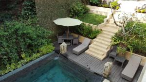 a swimming pool with an umbrella and a table and chairs at Villa Purnamasari in Ubud