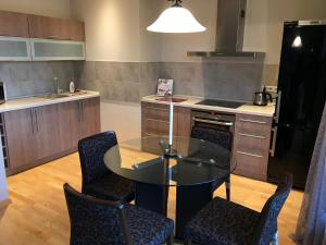 a kitchen with a glass table and some chairs at Lux Apartment in Druskininkai