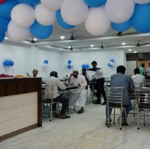 un gruppo di persone seduti ai tavoli in una stanza con palloncini di Hotel Chela a Kumbakonam