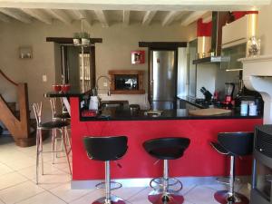 une cuisine avec un comptoir rouge et des tabourets dans l'établissement Maison entière avec cour dans le Chablisien, à Villy