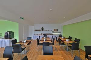 restauracja z drewnianymi stołami i krzesłami oraz kuchnią w obiekcie Business & City w Linzu
