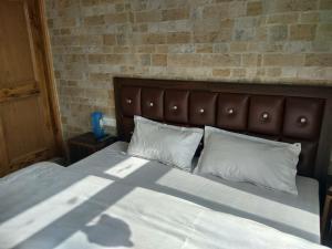 a bed with two white pillows and a brick wall at Shimla Facing Rooms Near Mall Road in Shimla