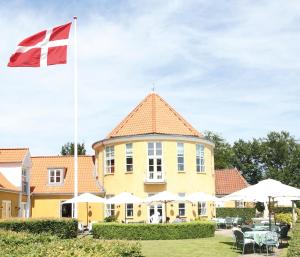 a flag flying in front of a yellow building at Fakkelgaarden Hotel & Restaurant in Kruså +34 photos