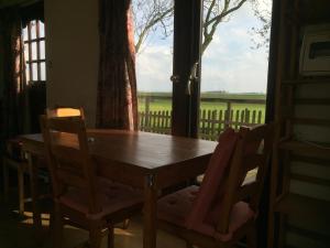 - une table et des chaises en bois dans une chambre avec fenêtre dans l'établissement Chalet westerham, à Winsum