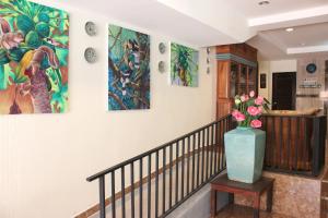 a staircase with paintings on the walls and a vase of flowers at B&B hostel @ Jomtien in Jomtien Beach