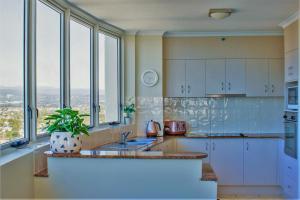 a kitchen with white cabinets and a sink and windows at Indigo Blue in Gold Coast