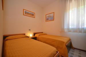 2 łóżka w małym pokoju z oknem w obiekcie Villaggio Orchidee w Bibione