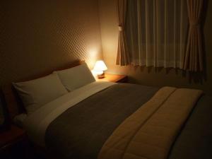 a bedroom with a large bed and a lamp at Aso Base Backpackers in Aso