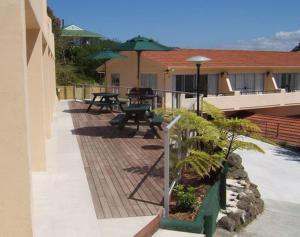 a patio with tables and umbrellas on a building at Paku Lodge Resort in Tairua