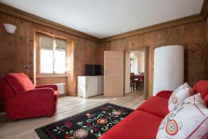 a living room with a red couch and two chairs at Casa del Sol Apartaments in Bormio