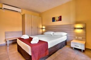 a bedroom with a large white bed and a table at Luna Holiday Complex in Mellieħa