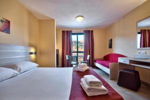 ein Hotelzimmer mit einem Bett und einem roten Sofa in der Unterkunft Luna Holiday Complex in Mellieħa + 73 Fotos