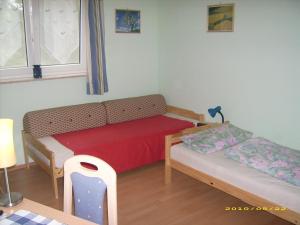 Habitación pequeña con sofá y cama en Pension "Am Tor zum Mainbogen", en Grettstadt