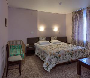 a bedroom with a bed and a chair and a window at Dva Kryla Inn in Yaroslavl