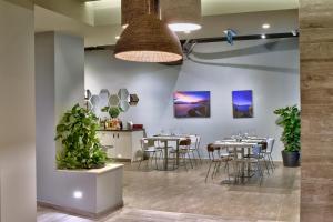 a dining room with tables and chairs and potted plants at Luna Holiday Complex in Mellieħa