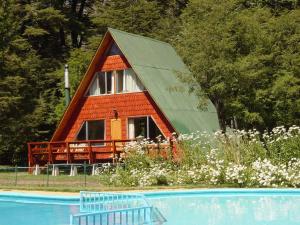 uma pequena cabana com um telhado inclinado ao lado de uma piscina em Cabañas Pachapulay em Valle Las Trancas