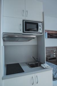 a white kitchen with a sink and a microwave at FirstSleep Boardinghouse Griesfeldstrasse München in Munich