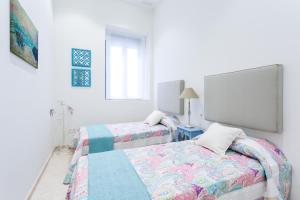 a white room with two beds and a window at Alohamundi Marqués de Paradas in Seville