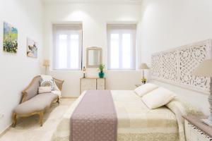 a white bedroom with a large bed and a chair at Alohamundi Marqués de Paradas in Seville