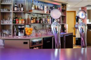 Le NeubourgにあるThe Originals City, Hôtel Acadine, Le Neubourg (Inter-Hotel)の紫色のカウンターとワイングラスを用意したバー