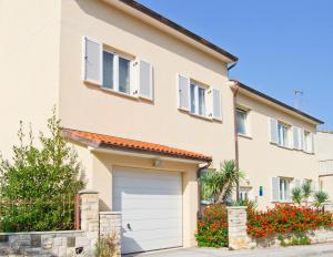 a house with a garage and flowers in front of it at Apartments Nicole in Pula