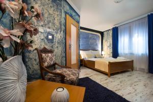 a room with a bedroom with a bed and a chair at Wellness Penzión Vila Mery in Poprad