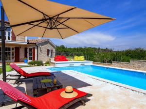 a pool with two chairs and an umbrella at Splendid Villa with Private Swimming Pool in Baderna