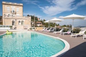 uma piscina com cadeiras e guarda-sóis e um edifício em Villa Contessina em Cossignano