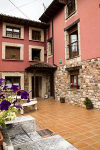 a pink building with flowers in front of it at Apartamentos la Regoria in Arenas de Cabrales