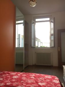 1 dormitorio con 1 cama roja y 2 ventanas en Appartamento Mosaico 22161, en Rovereto