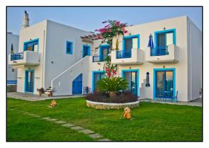 a large white building with blue doors and a yard at Bella Vista Stegna in Archangelos