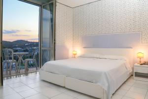 ein weißes Schlafzimmer mit einem Bett und einem Balkon in der Unterkunft Hotel Loreley in Ischia