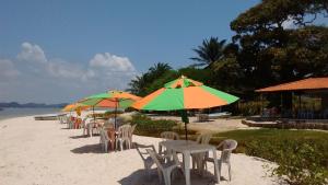 a row of tables and chairs with umbrellas on a beach at Pousada Luar de Monte Cristo in Araripe de Baixo